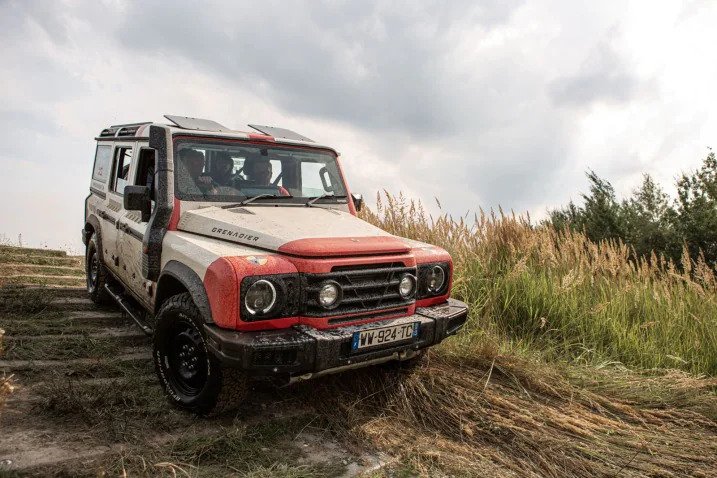 A 2021 Ineos Grenadier driving outside through grass