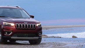 A red 2021 Jeep Grand Cherokee driving at the edge of the ocean.