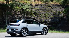 A light-gray 2021 Volkswagen ID.4 electric crossover SUV parked on a road next to a rocky cliff