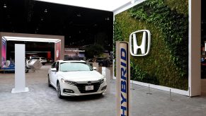 A white 2021 Honda Accord, one of the best midsized sedans on sale today, shot in an auto show booth from the front 3/4 angle