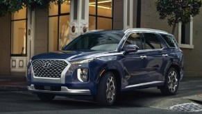 A dark blue 2021 Hyundai Palisade pulling out of a side street.