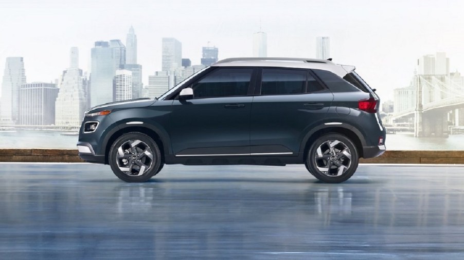 A dark blue 2021 Hyundai Venue with a city skyline behind it.