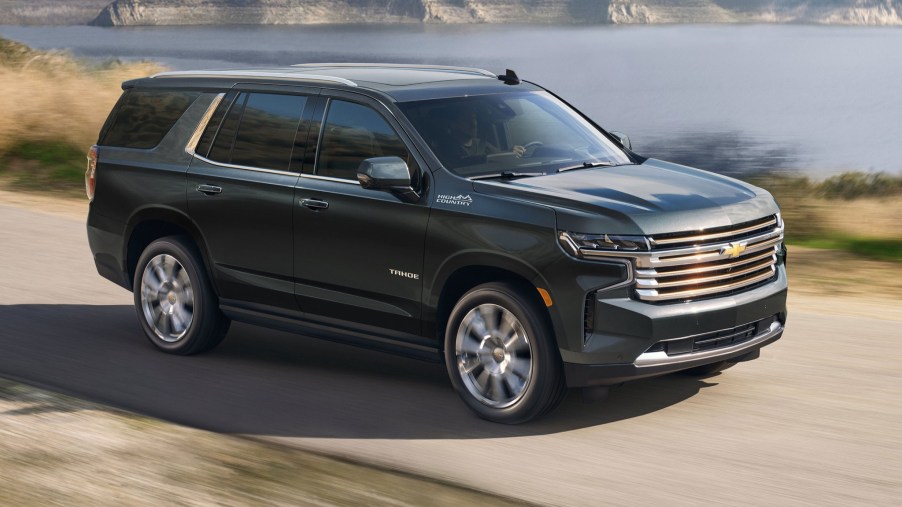 black 2022 Chevrolet Tahoe High Country driving near a lake