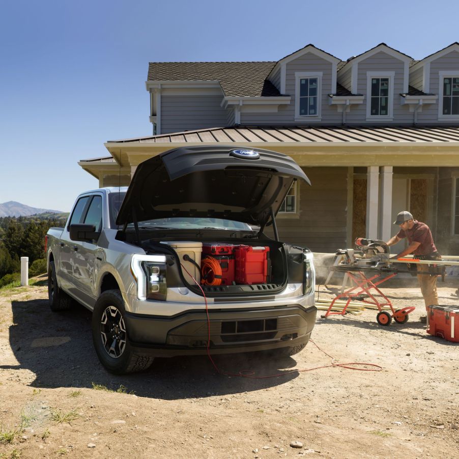 The front of a 2022 Ford F-150 Lightning with the frunk open at a construction site during a house build.