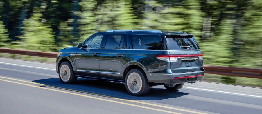 A dark-blue 2022 Lincoln Navigator SUV traveling on a highway past a blur of trees