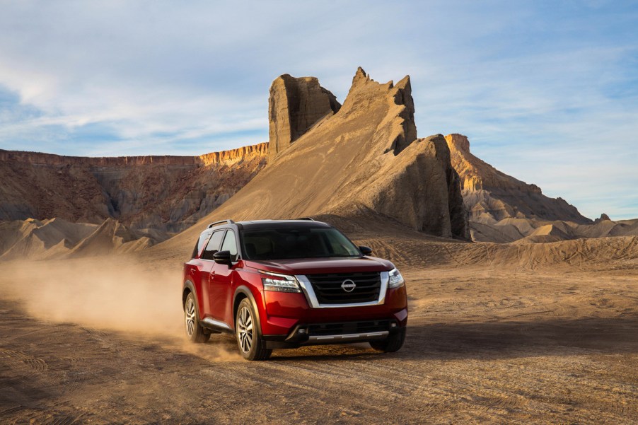 A red 2022 nissan pathfinder driving through a desert