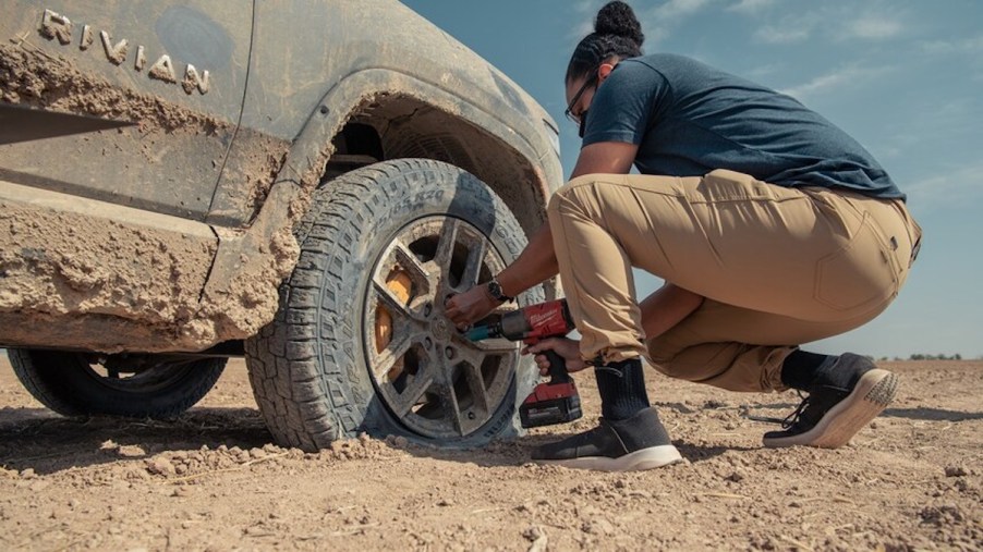 A man fixing a flat tire on the Rivian R1T