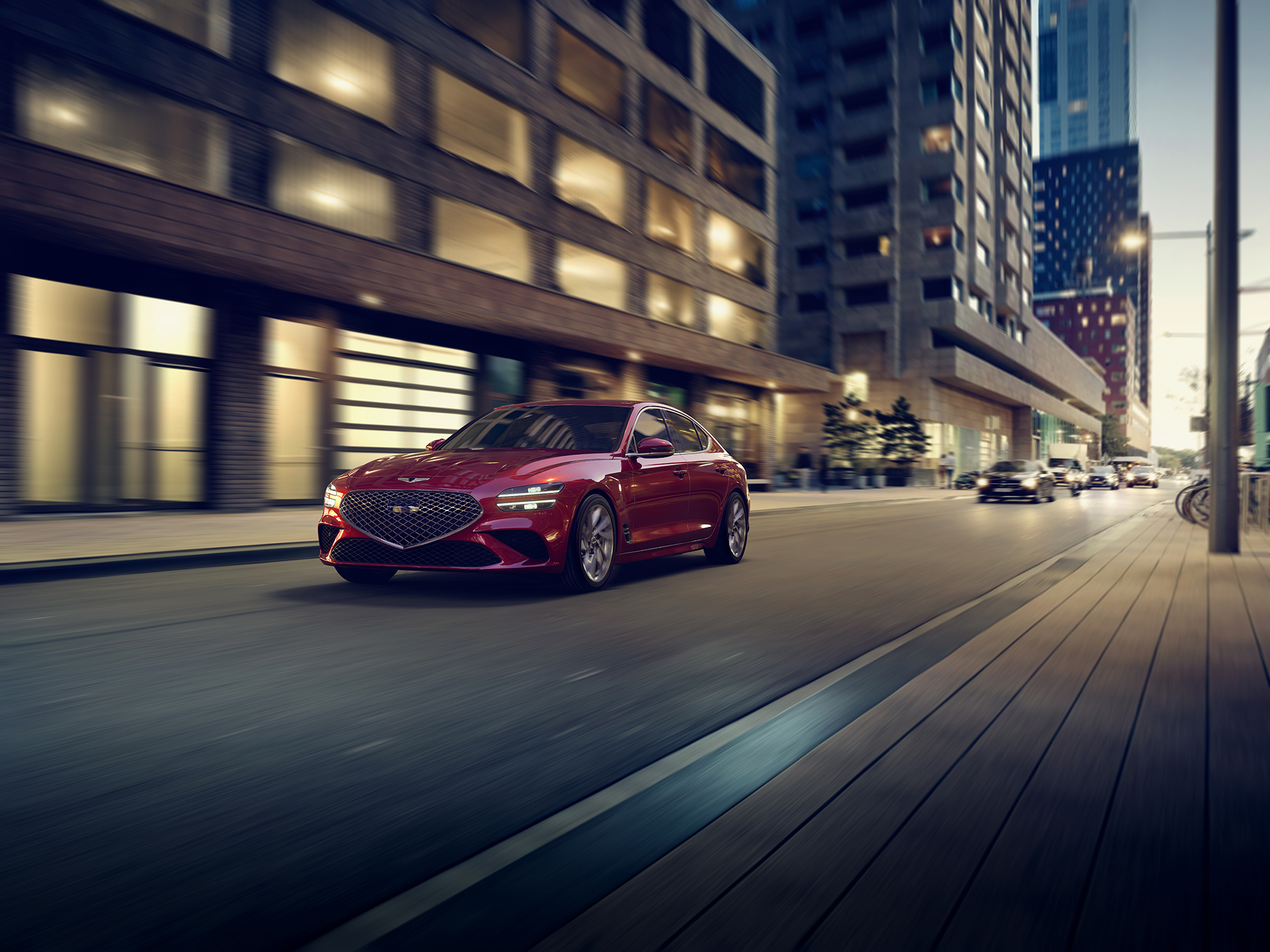 A red 2022 Genesis G70 rolling down a city street at night shot from the front 3/4