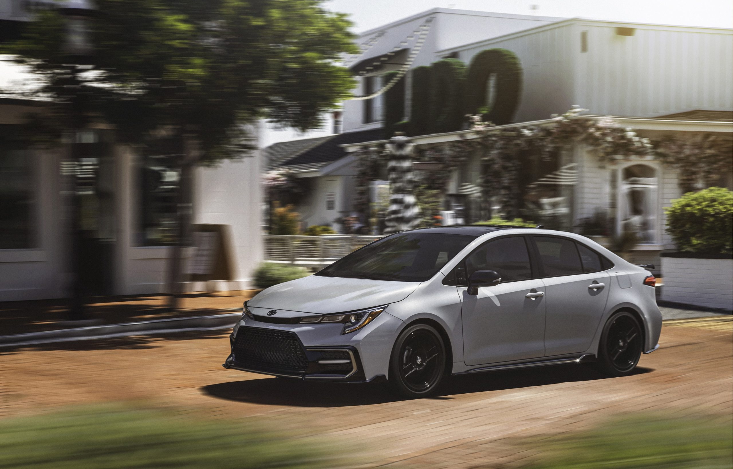 A grey 2022 Toyota Corolla Apex shot from the front 3/4 on a busy street