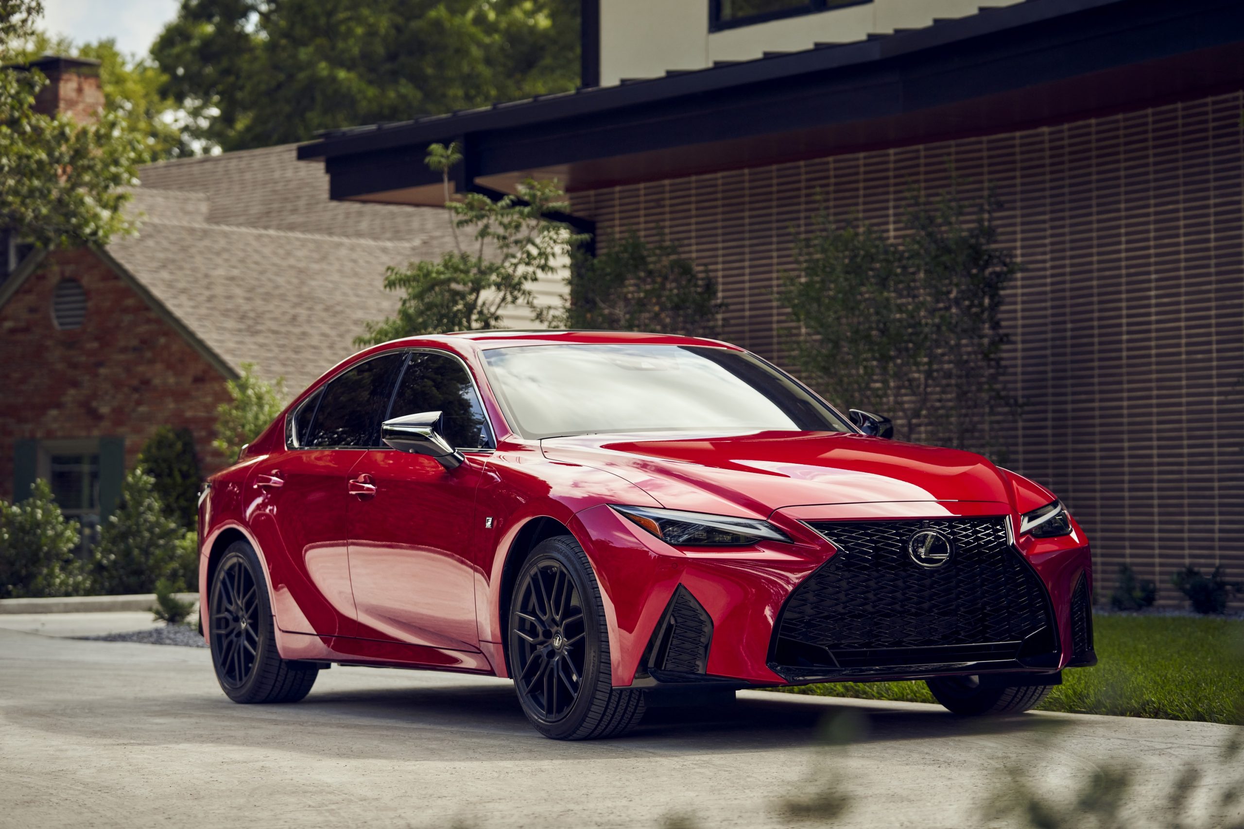 A red Lexus IS F-Sport shot from the front 3/4 in a residential area