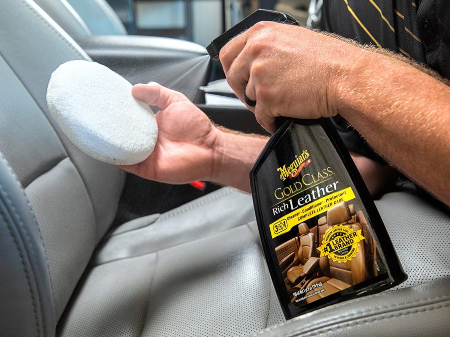 Spraying an applicator pad with Meguiar's Gold Class Rich Leather spray