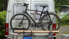 A white German RV with a gray bicycle on its ladder-mounted rack