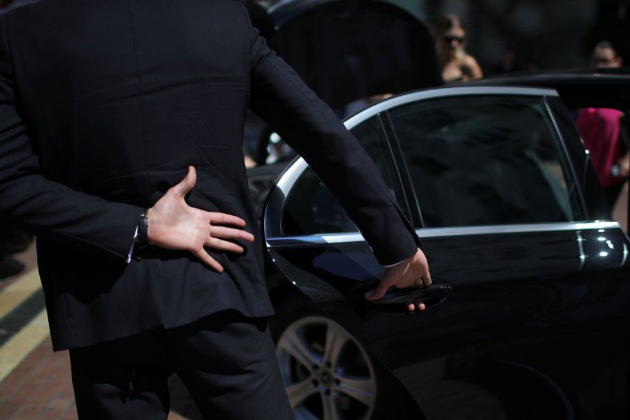 A security guard opening and closing a door for a celebrity client