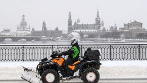 A snow plow attached to an ATV scrapping the road.