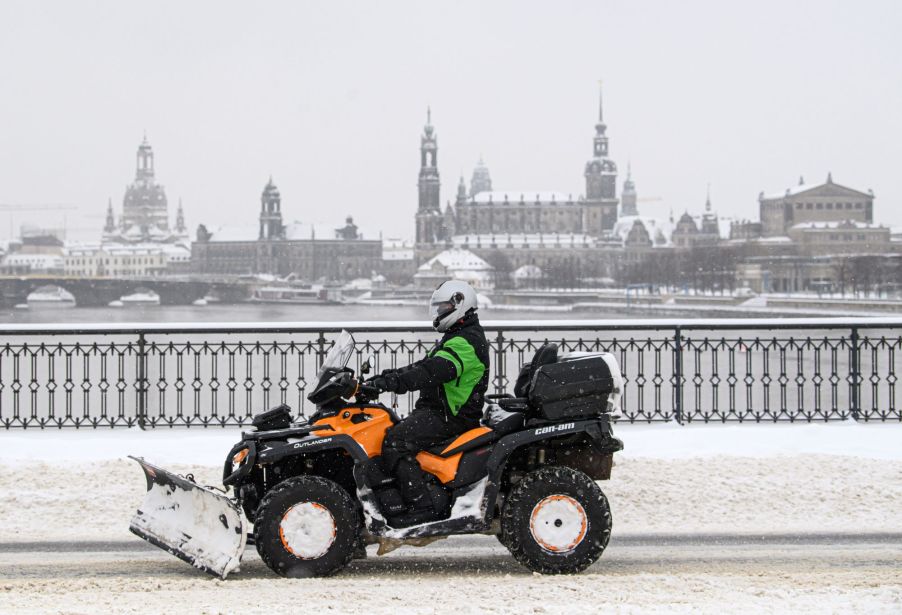 A snow plow attached to an ATV scrapping the road.