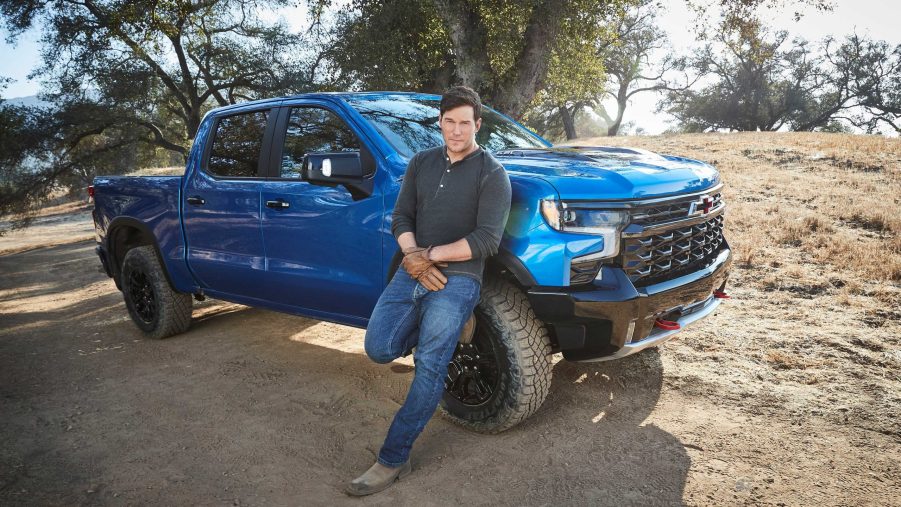 Chris Pratt leaning up against a blue 2022 Chevy Silverado ZR2