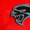 A Dodge Challenger Hellcat logo on a red car.