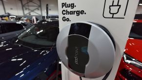 An EV charging station that says "Plug. Charge. Go." inside of a building next to a blue car.