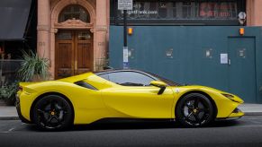 Yellow Ferrari SG90 sitting in front of a green and brown building on the curb.