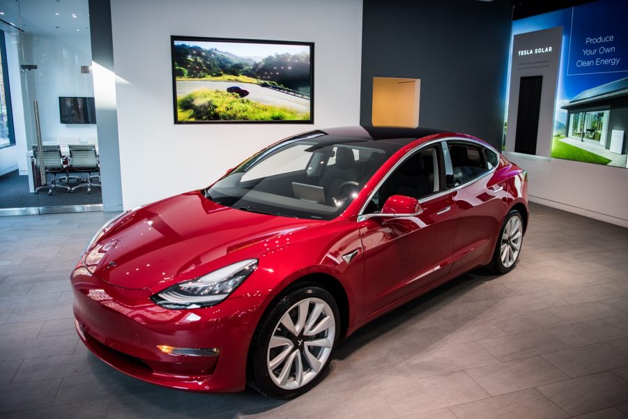 A red Tesla Model 3 in a showroom