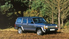 Gray 1993 Jeep Cherokee parked next to a forest