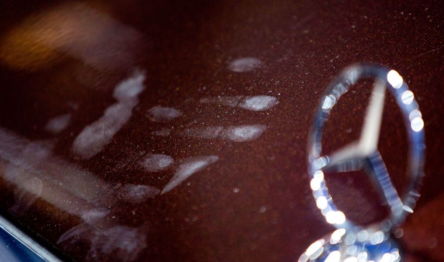 A ghostly white handprint on a red Mercedes car.