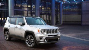 A silver Jeep compass sits outside of a hotel.