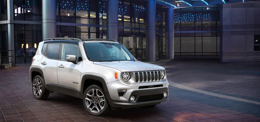 A silver Jeep compass sits outside of a hotel.