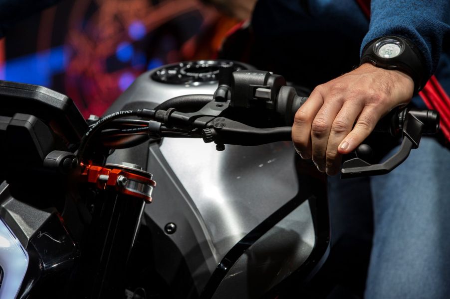 A driver with their hands on a KTM motorcycle's brakes