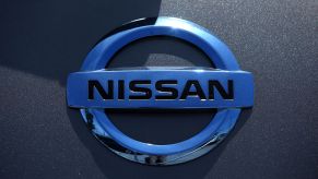 Chrome Nissan logo on a grey car.