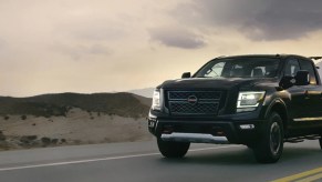 A black Nissan Titan driving down a highway.