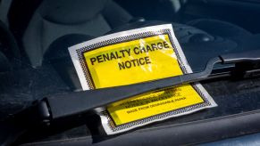 A bright yellow parking violation ticket on a vehicle under the windshield wiper.