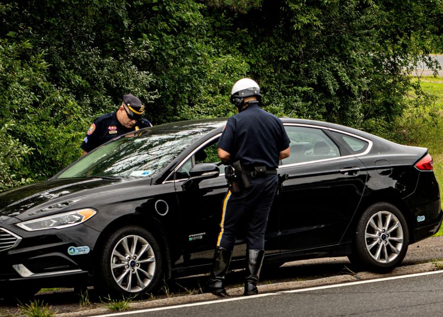 Two police officers pulling over a for unsafe or illegal activity black car.