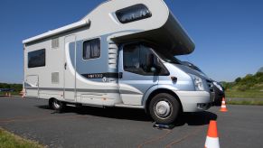 RV sitting on a highway with traffic cones and clear skies.