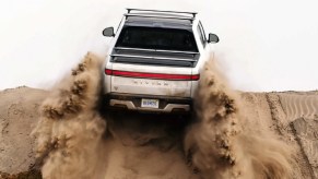 A white 2022 Rivian R1T climbing up a dirt hill.