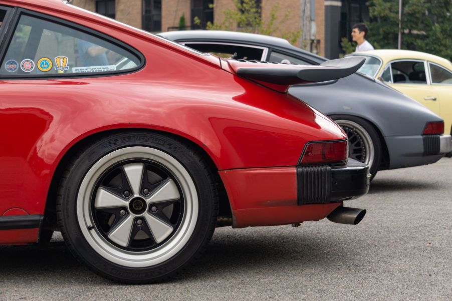 Side view of the rear halves of a red, gray, and yellow classic Porsche 911