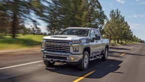 Silver 2022 Chevrolet Silverado 2500HD driving by some trees