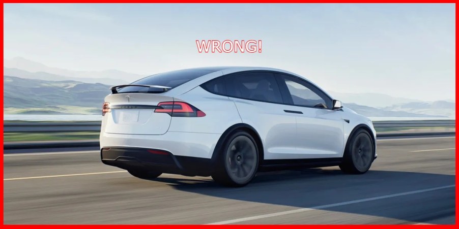 A white Tesla Model X electric SUV is driving on the road.