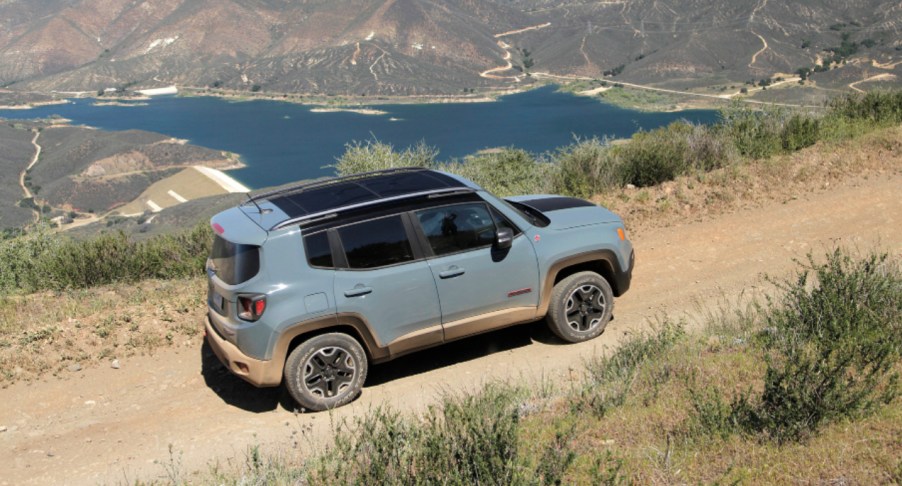 A green Jeep Renegade Trailhawk small off-road SUV is off-roading on a trail.