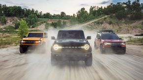 Three 2021 Ford Bronco SUVs driving on a gravel road