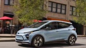 An ice blue 2022 Chevy Bolt driving through a city.