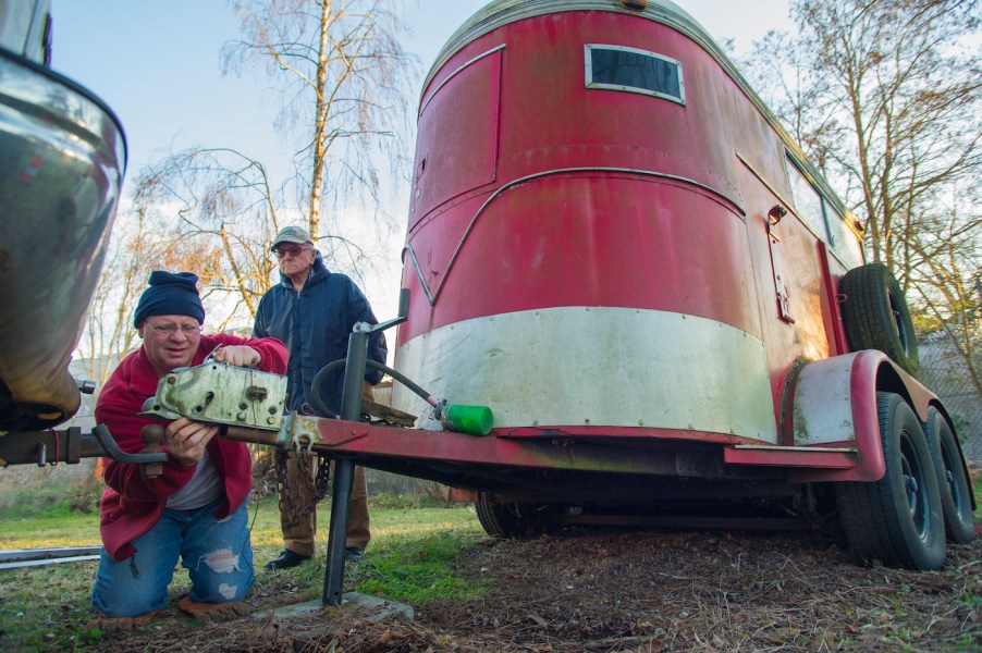 A man hitches a horse trailer to a ball hitch for towing