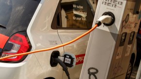 An electric car stands at a charging station to recharge for full range, which is not the same as mpge