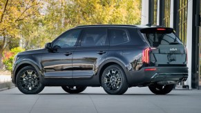 A dark-colored 2021 Kia Telluride sits outside of a house.