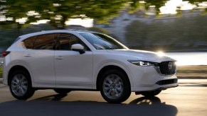 A white 2022 Mazda CX-5 driving by water.