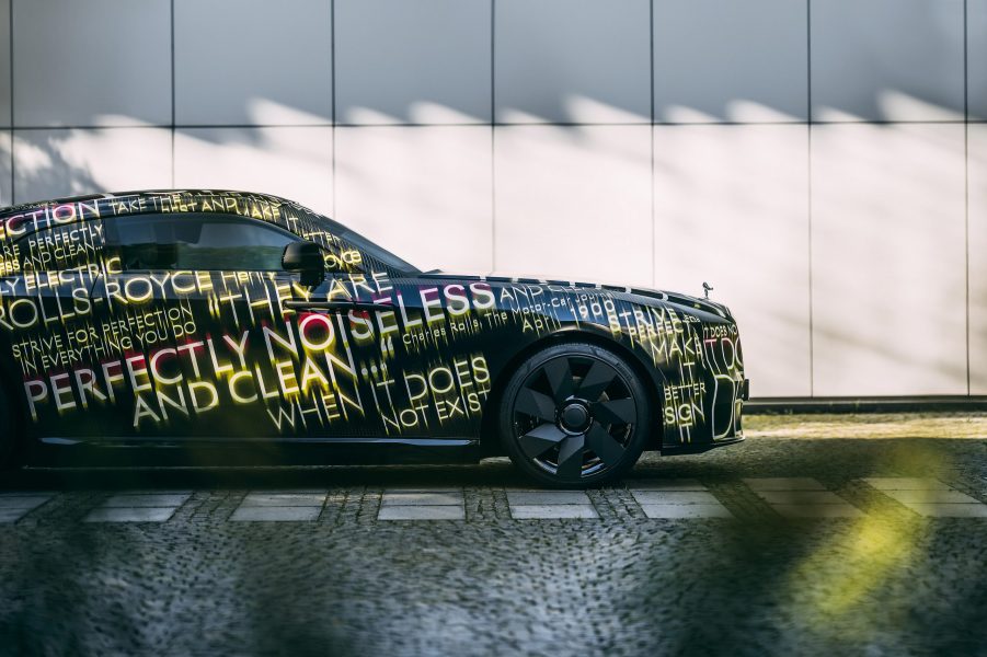 A black and livery with gold text laid over the bodywork of the new Rolls Royce Spectre luxury car