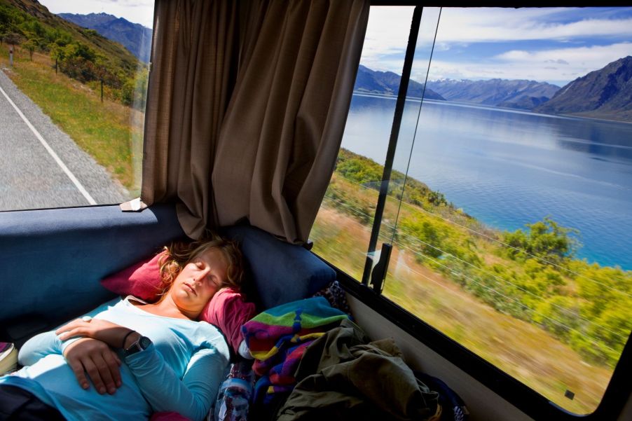 A woman sleeping in the back of an RV during a trip in South Island, New Zealand