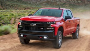 Red 2021 Chevrolet Silverado LT Trail Boss driving on a dirt road