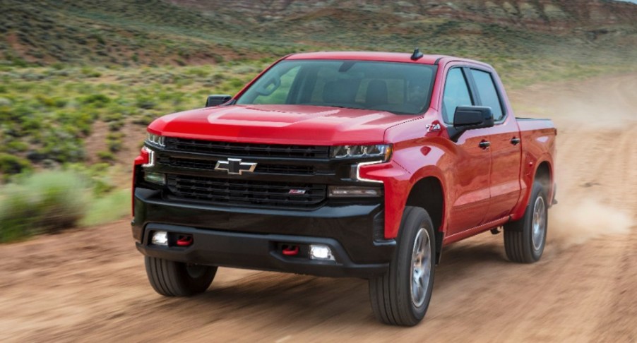 Red 2021 Chevrolet Silverado LT Trail Boss driving on a dirt road