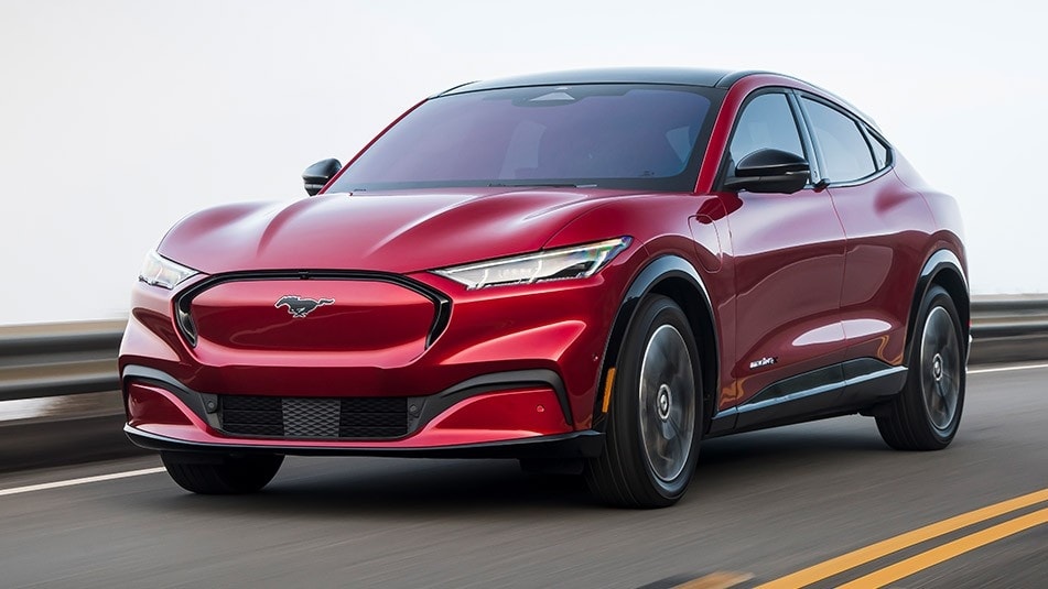 A red 2021 Ford Mustang Mach-e driving down a highway. 